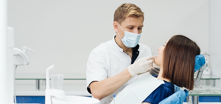 https://cdn1.pokupon.ua/uploaded/new_campaign_pictures/852501/data/main720x340/close-up-portrait-beautiful-young-lady-sitting-dental-chair-while-stomatologist-hands-sterile-gloves-holding-tooth-samples.jpg?1772208490